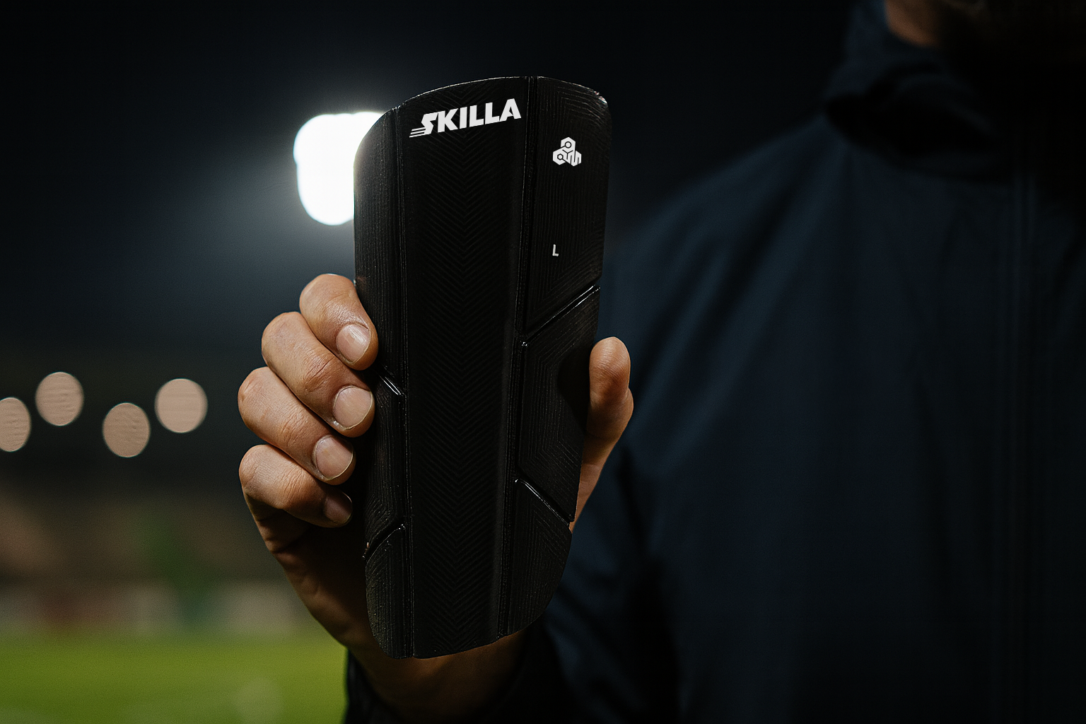 Fußballtrainer mit SKILLA Smart Shin Guards in der Hand, Fokus auf Produkt
